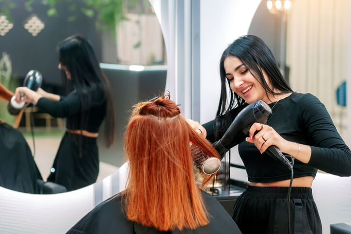 A cosmetology school grad styling hair in a salon