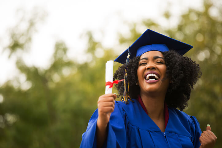 A beauty school graduate at graduation wearing a cap and robe