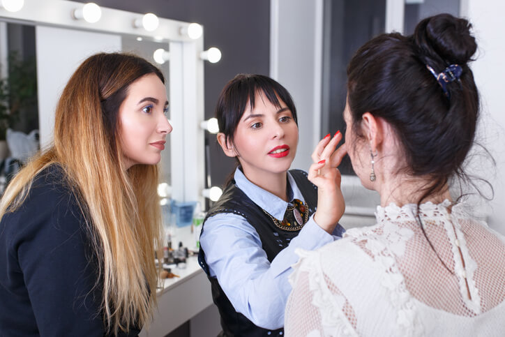 A cosmetology educator observing a student applying makeup to someone