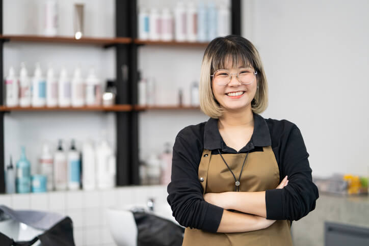 An owner with cosmetology skills posing in her salon