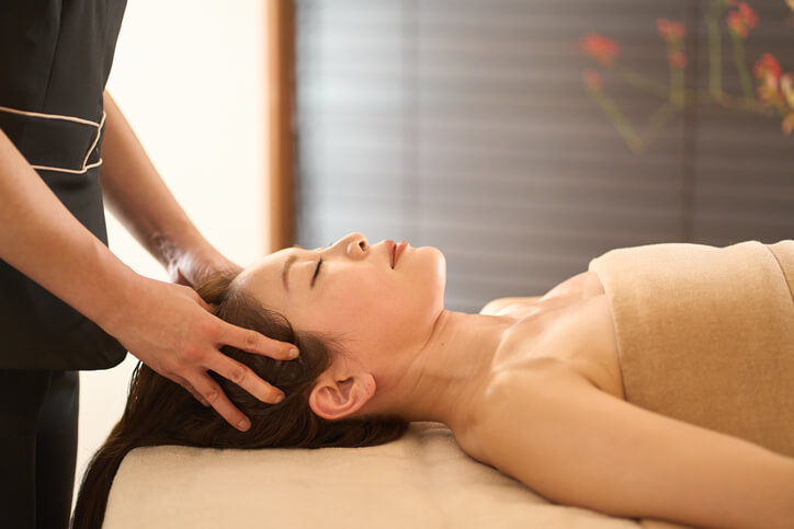 A Korean head spa training grad giving a client a scalp massage