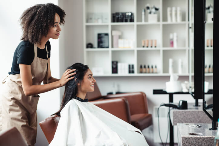 A cosmetology graduate washing hair while owning a beauty salon