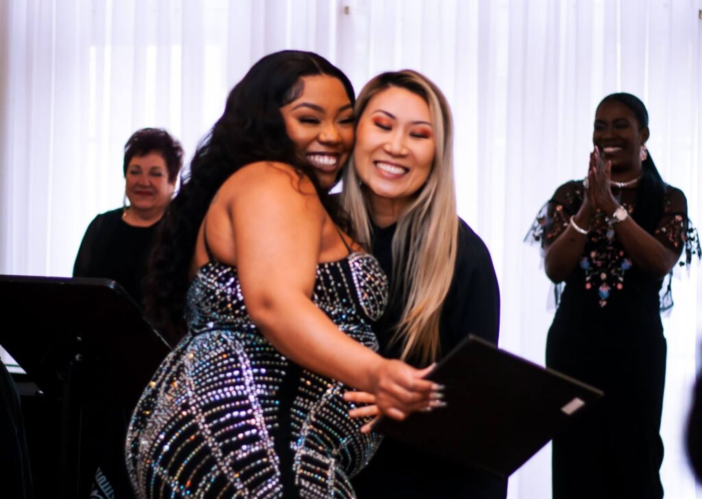 A cosmetology school graduate hugging an instructor