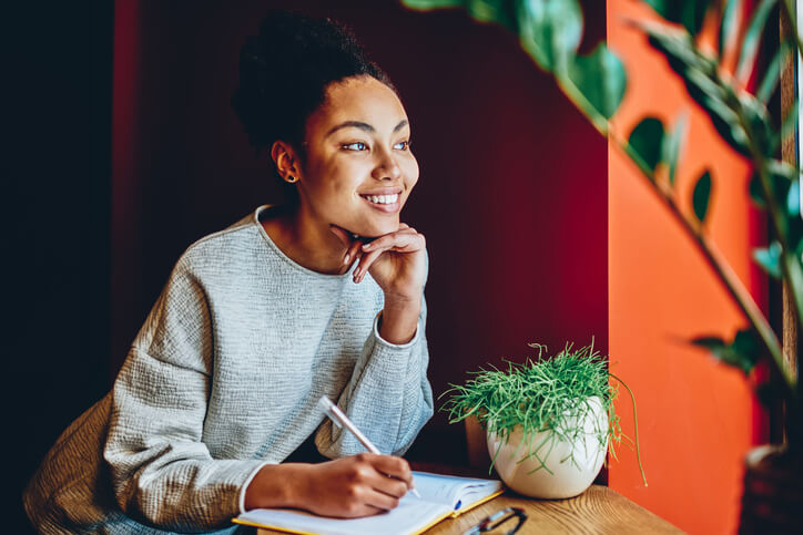 Pensive cosmetology student setting goals at a desk