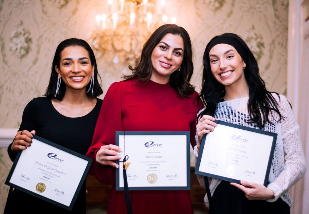 A trio of cosmetology school graduates holding up their diplomas