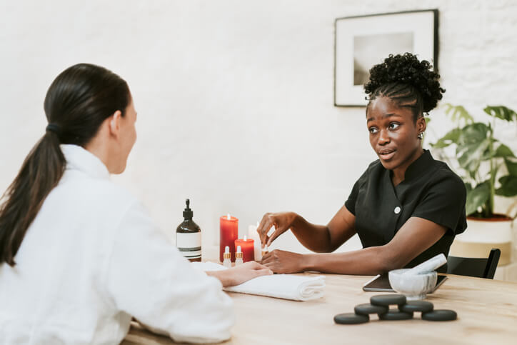 cosmetology school graduate painting a client’s nails